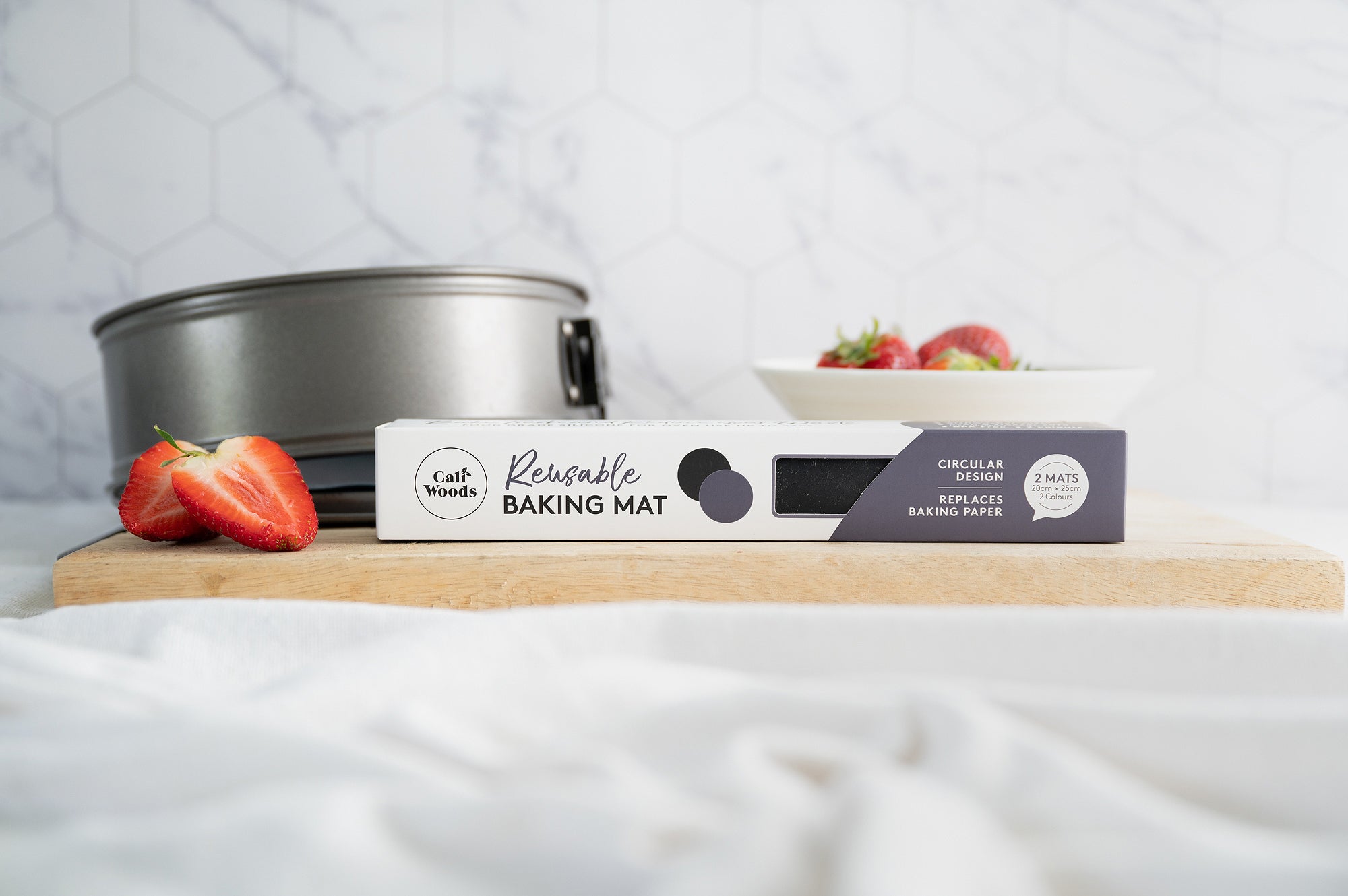 Circular silicone cake tin liners styled with strawberries and a cake tin