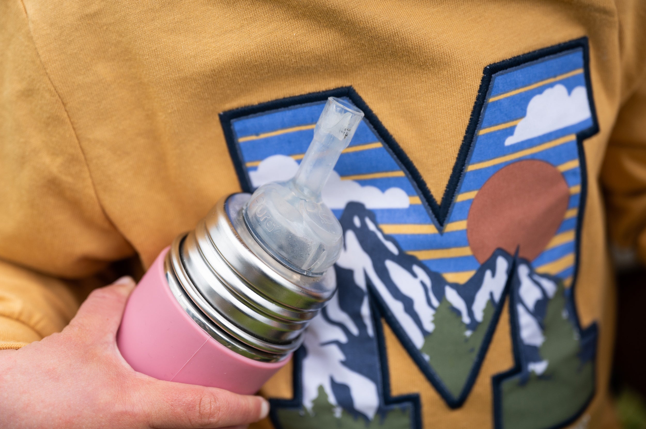 Pura kiki water bottle held in a boy's hand, close up of the lid.