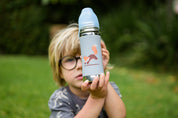 Boy on grass holding up a toddler stainless steel drink bottle 