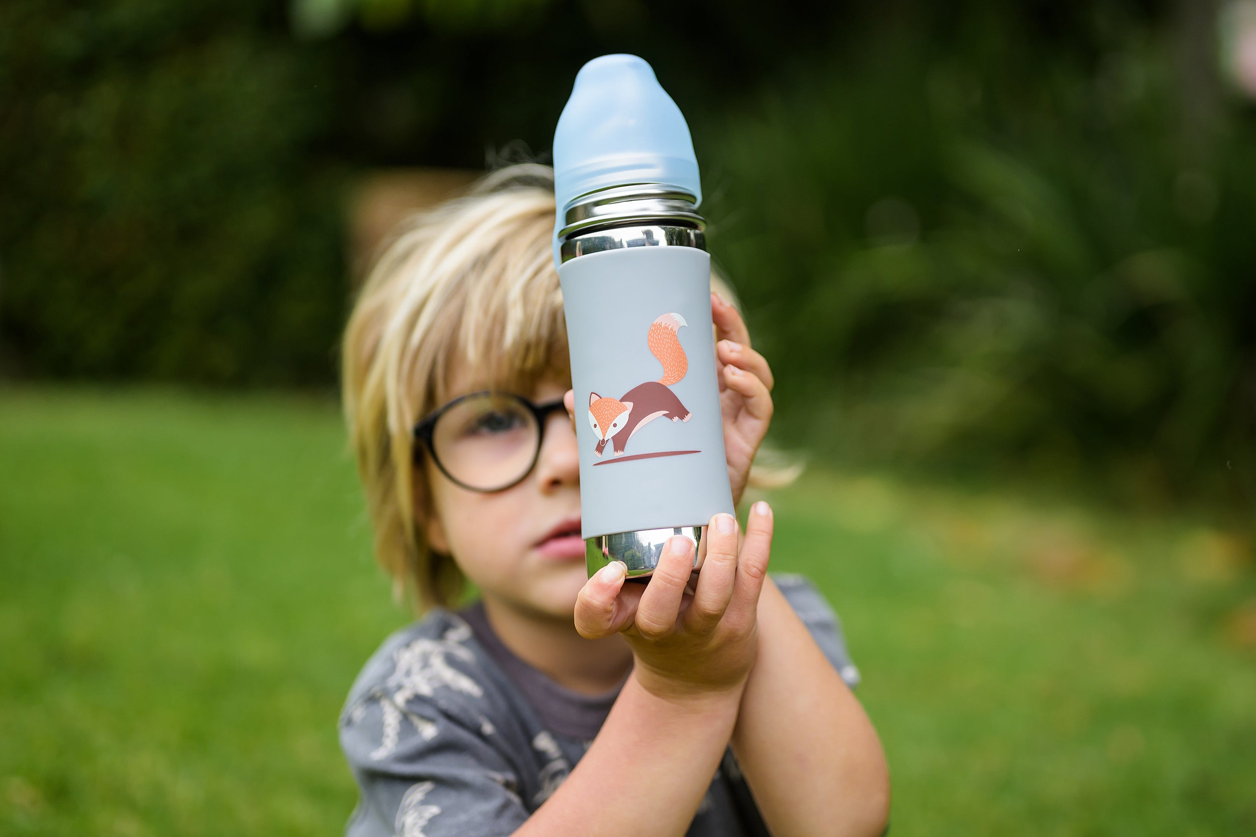 Boy on grass holding up a toddler stainless steel drink bottle 