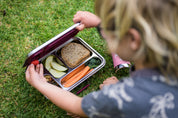 Child grabbing food from stainless leak proof lunchbox 