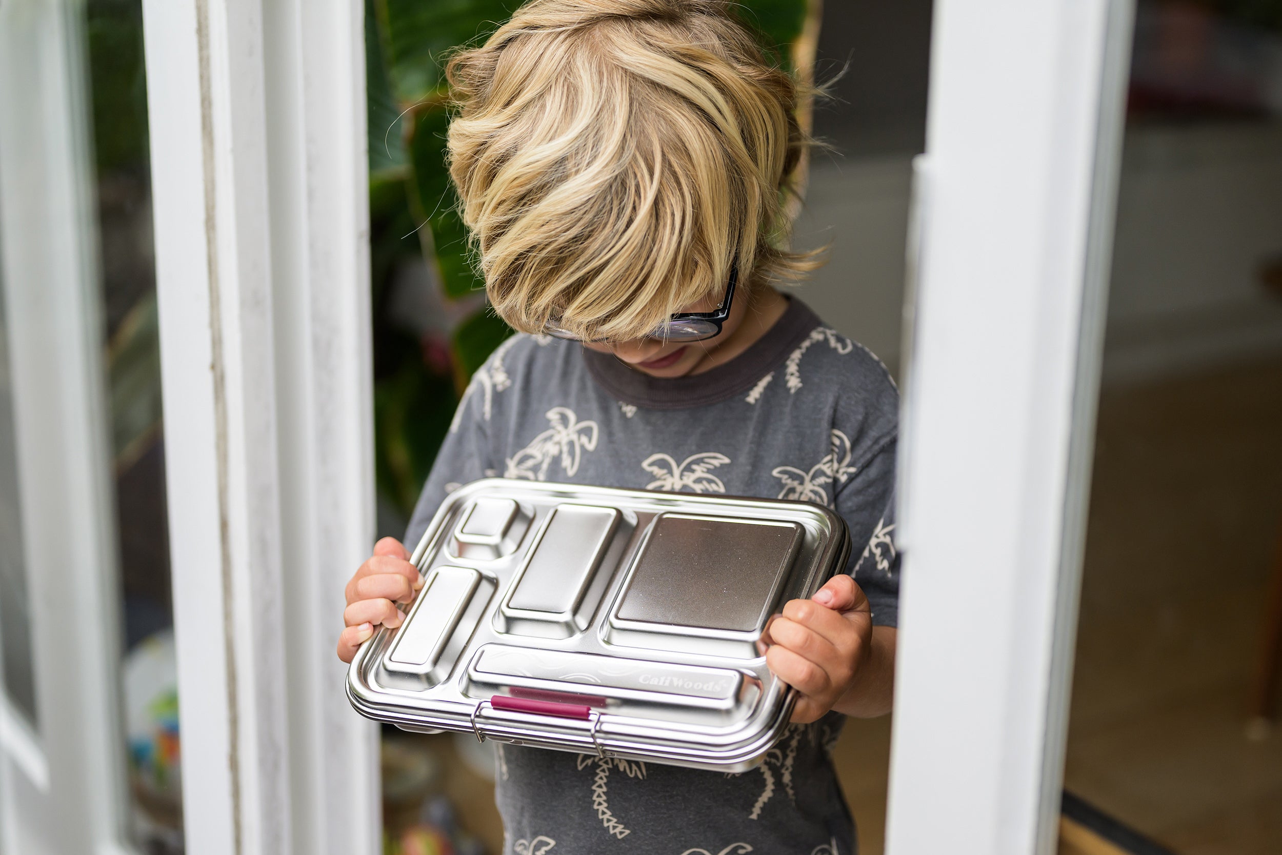 Young boy in doorway holding a CaliWoods Stainless Bento Lunchbox