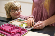 Boy picking food from a compartment in the CaliWoods Bento Toddler Lunchbox