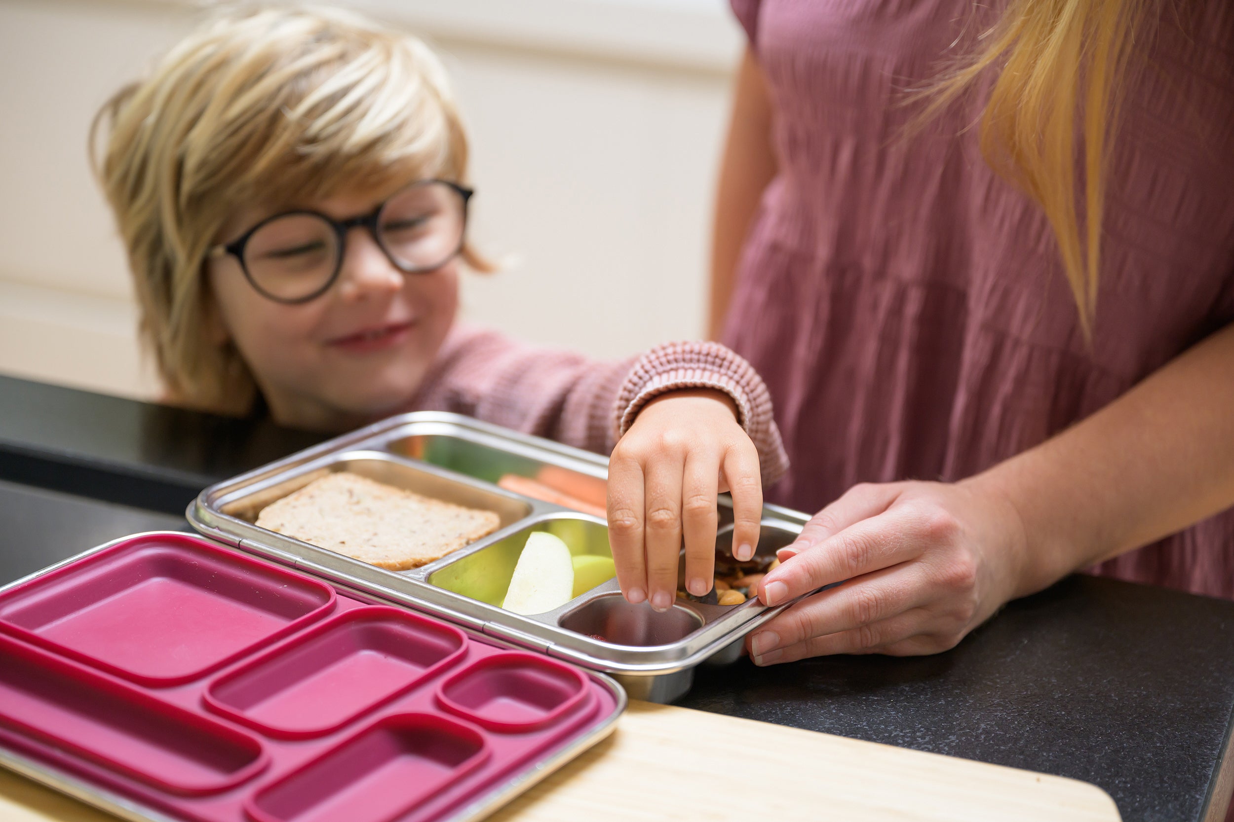 Boy picking food from a compartment in the CaliWoods Bento Toddler Lunchbox