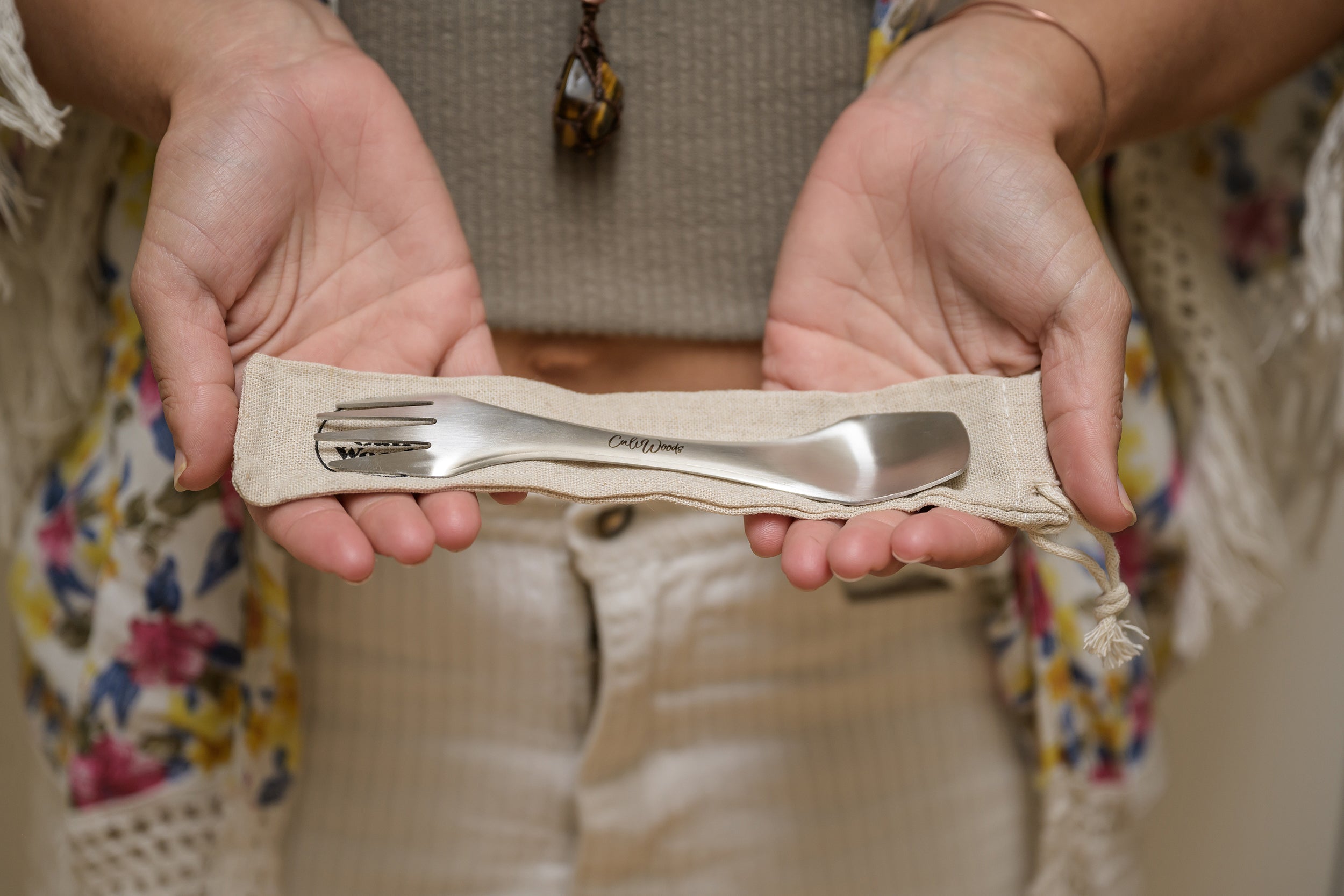 Woman holding a CaliWoods Stainless Spork to go cutlery with the carry bag in her hands