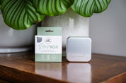 Aluminium Travel Soap box in the packaging with another CaliWoods Soap Box next to it on a wooden bench with plant in the background