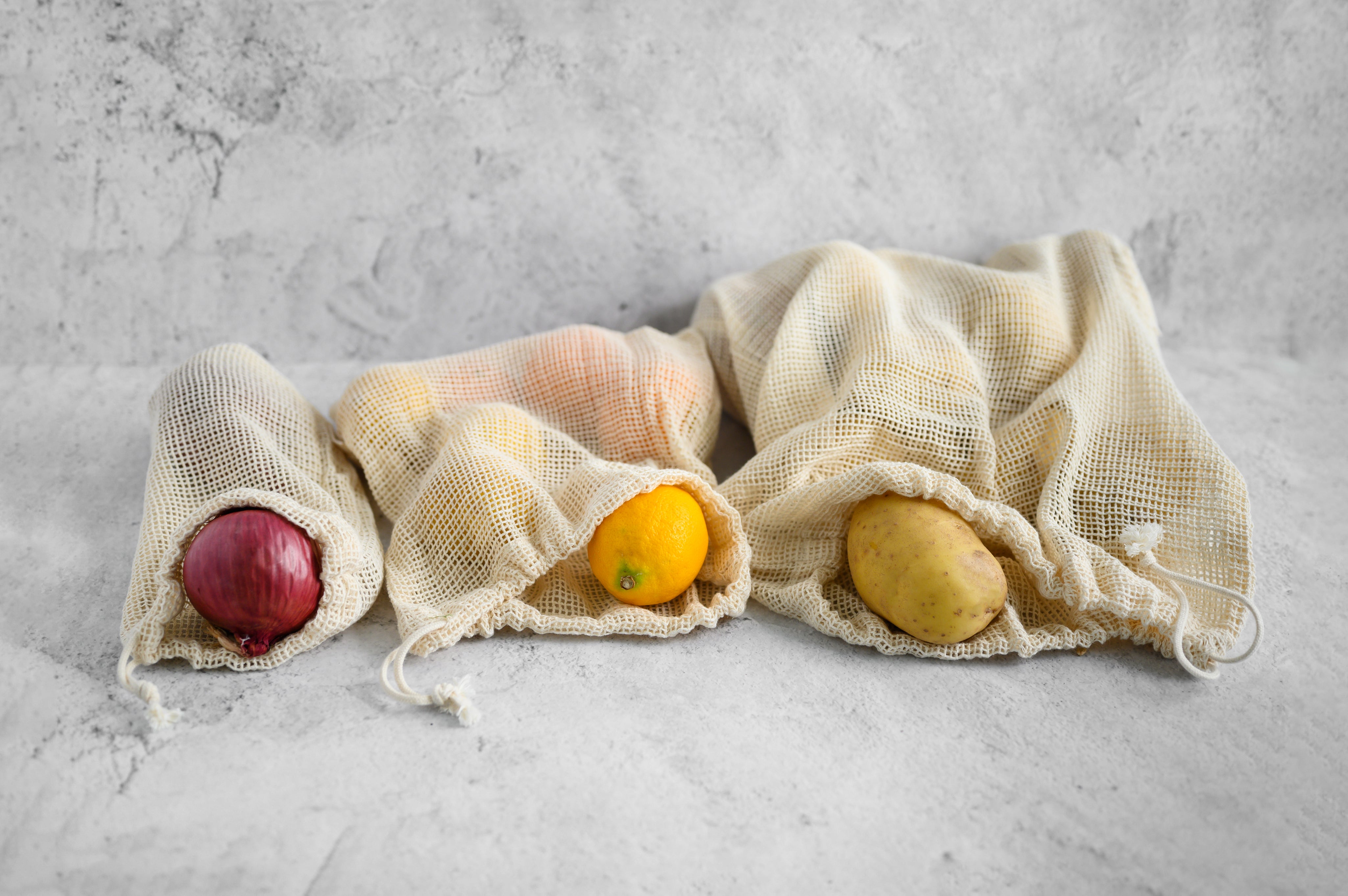 CaliWoods organic cotton Produce bags with potatoes, lemons and red onion n a tile background