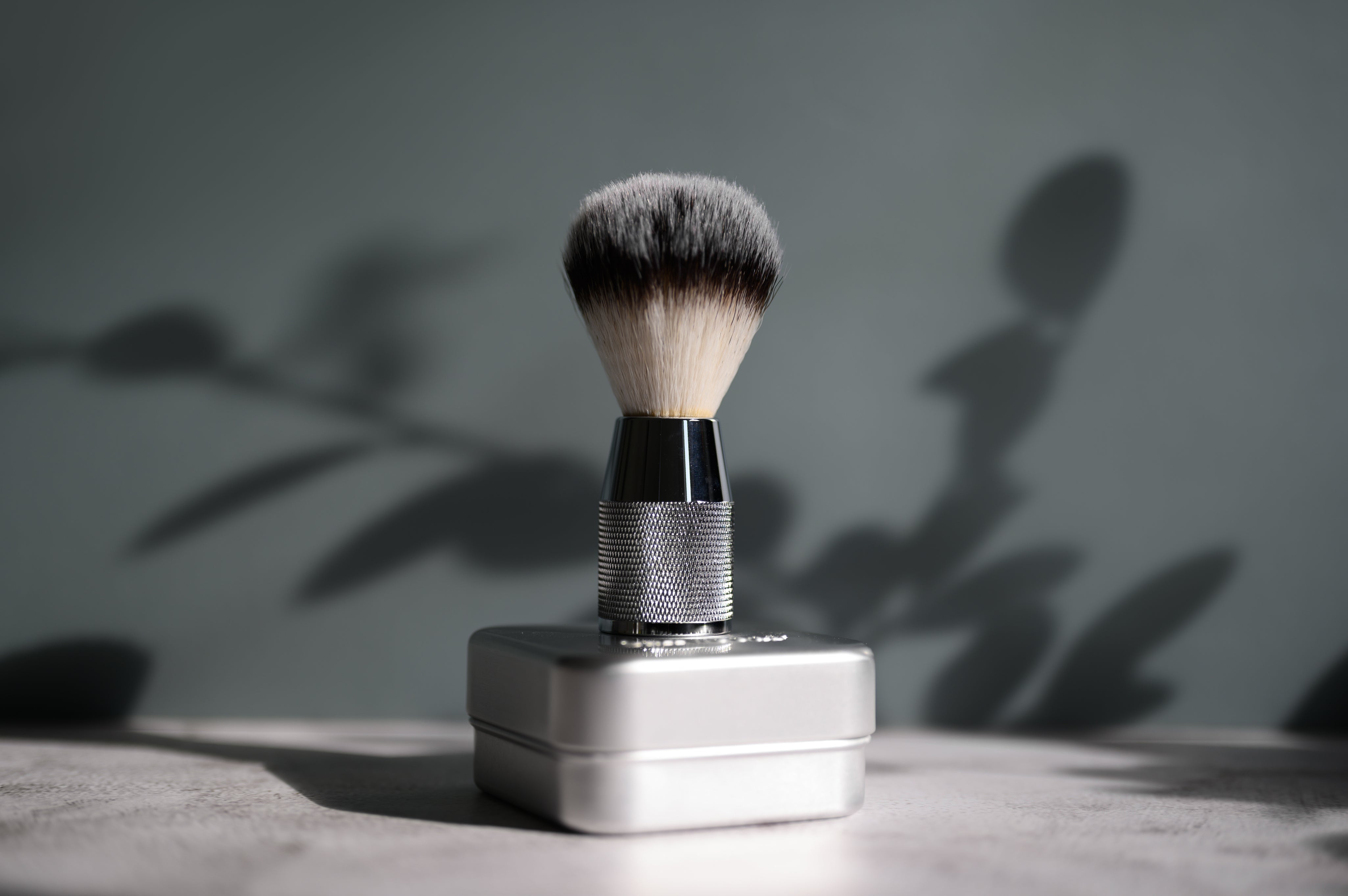 silver shaving brush with metal soap holder with drip tray on grey background