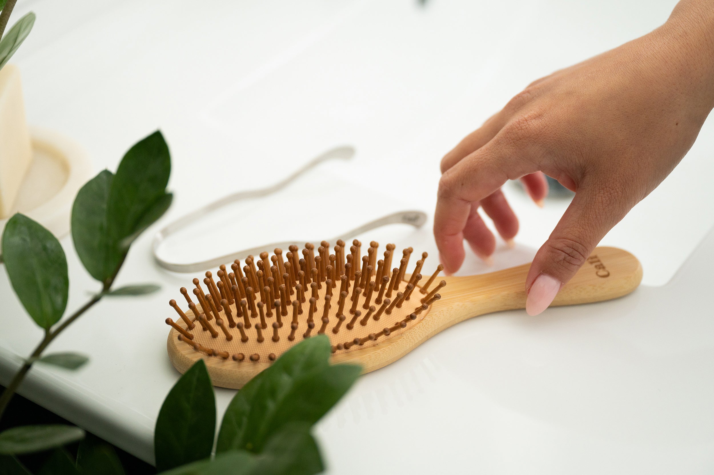 Person reaches for a bamboo hairbrush from CaliWoods 