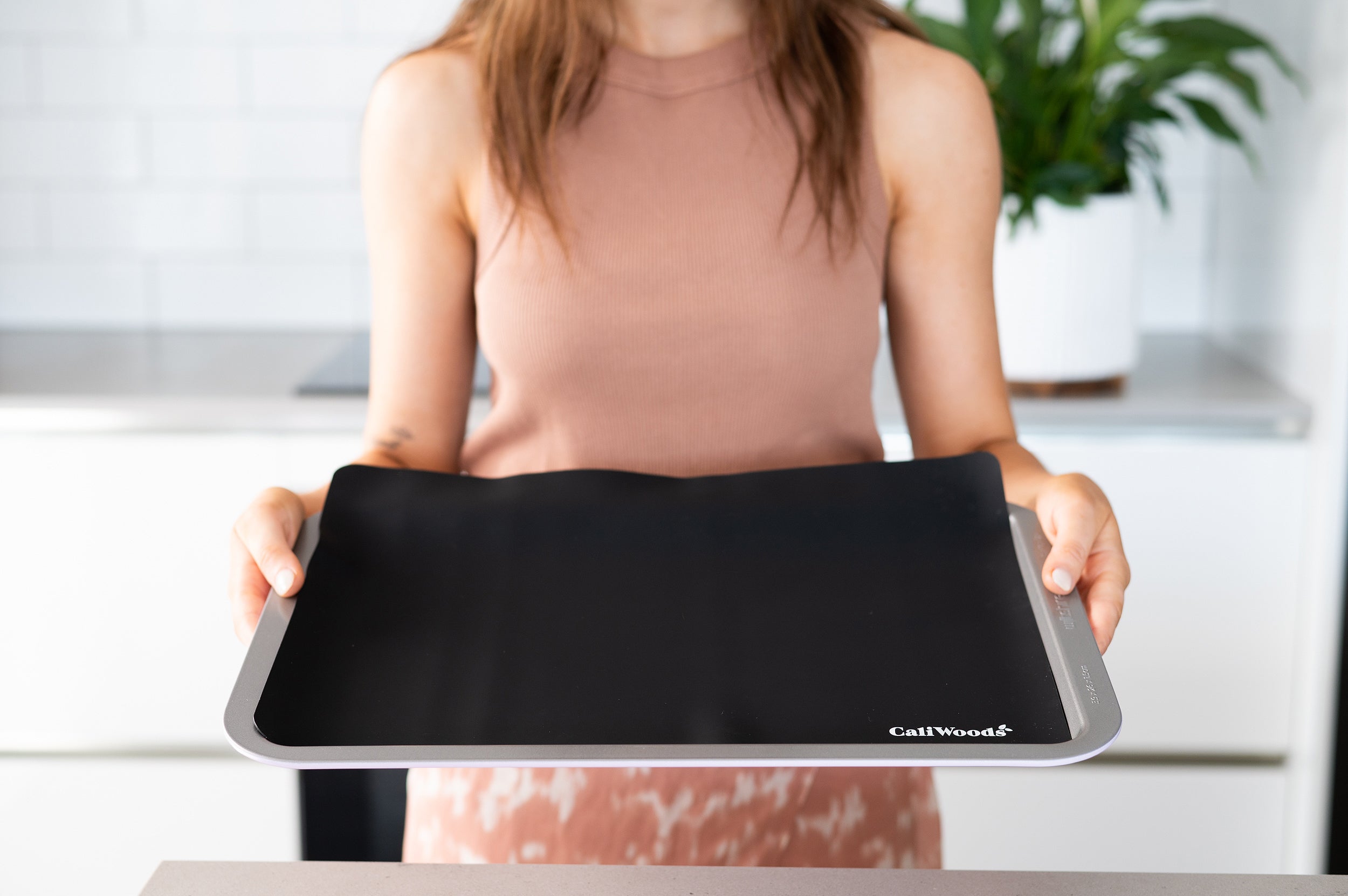 Reusable Baking Mat in black with woman holding baking tray 