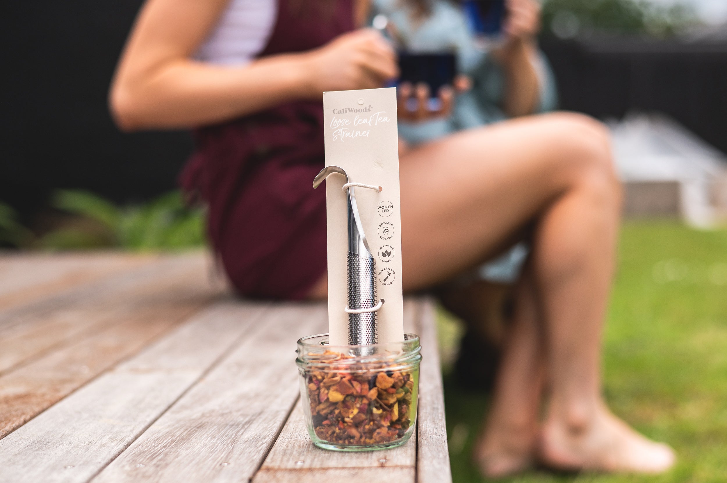 Tea Infuser sitting in a jar of loose leaf tea with people blurred in the background