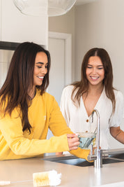 Two women filling up a cup with hot water for tea