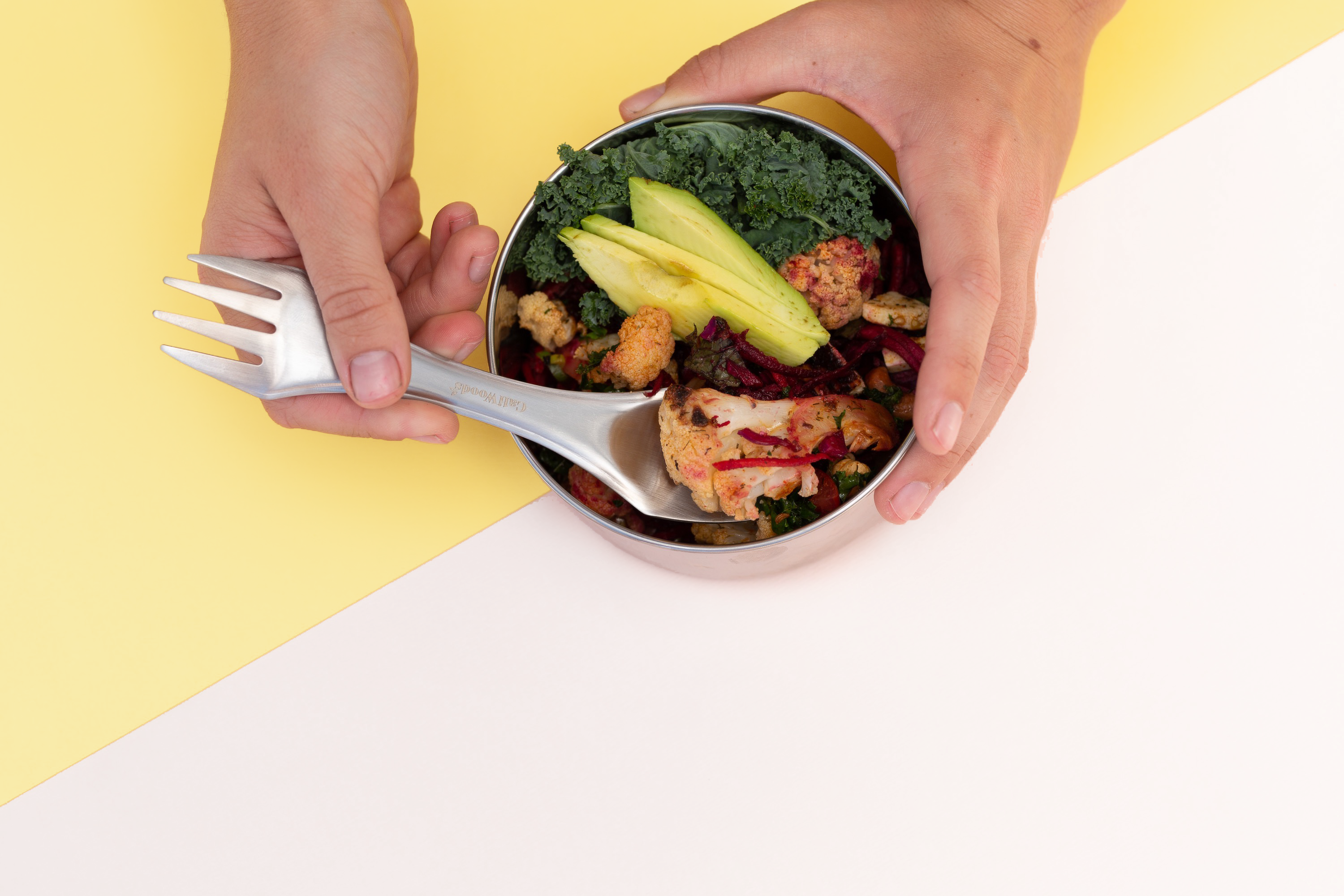 CaliWoods Spork being used for lunch, dipping into salad in a stainless container